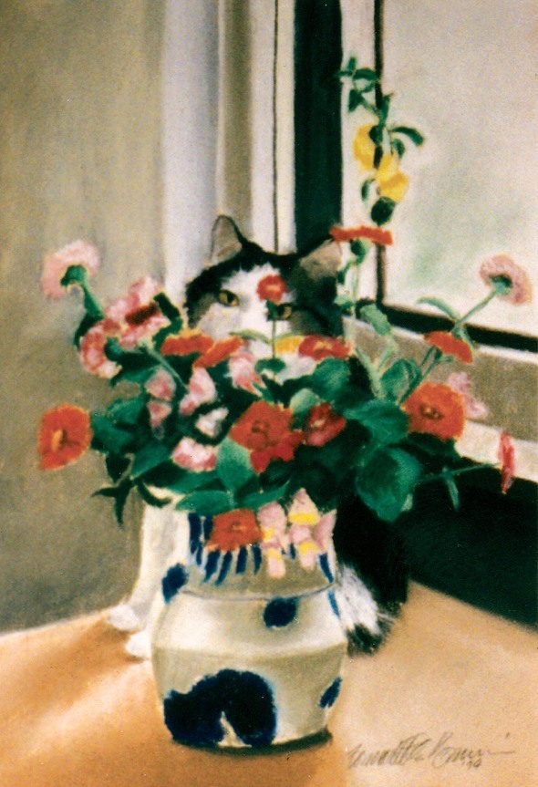 cat sitting behind vase of flowers